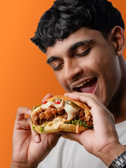 A customer mid-bite with a HOWLERS chicken burger